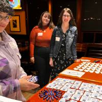 Three alums standing at the welcome table together.